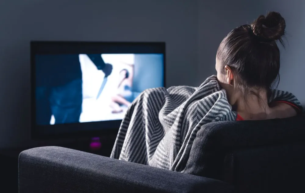 Woman watching scary movie on screen